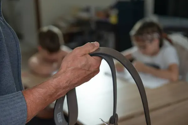 stock image brown leather belt in male hand, man confronts child, two boys doing homework at table, authoritarian parental discipline and punishment, generation gap, Parenting struggles