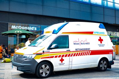 Austrian ambulance stationed in front Vienna Central Train Station, emergency response in busy city setting, efficient medical response, Vienna, Austria - August 1, 2024 clipart