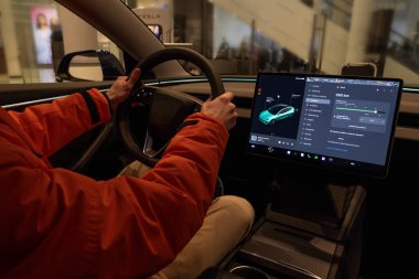 close-up male hands on steering wheel, Tesla electric car model 3 Interior, cockpit modern EV technologies car manufacturing, such autopilot, eco-friendly engines, Berlin, Germany - February 17, 2024 clipart