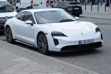 Lüks batarya elektrikli beyaz Porsche Taycan, modern kıvrımlı ve lüks performanslı şık elektrik tasarımı, kentsel çevre, Berlin, Almanya - 15 Ağustos 2024