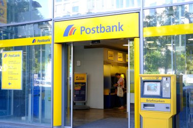 parlak sarı cephe Avrupa Bankası Postası şubesi müşterileri içeri davet ediyor, müşteri Almanya, Frankfurt 'taki ATM modern banka şubesiyle etkileşime geçiyor - 28 Mayıs 2024