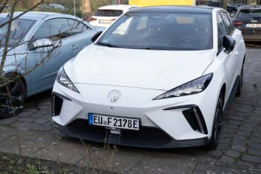 Parke sokağına park edilmiş parlak beyaz MG4 EV, modern ve şık tasarım Morris Garajları, SAIC Motor, sorunsuz bir şekilde kentsel çevreye, Berlin, Almanya - 20 Ağustos 2024