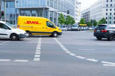 Sarı DHL dağıtım minibüsü şehir trafiğinde geziniyor, zamanında teslimat garantisi, şehir ortamları için yeşil lojistik, Frankfurt - 28 Mayıs 2024