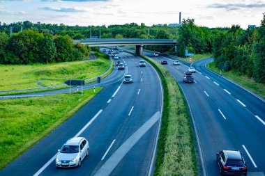 Modern çoklu şeritli otoyol, doğal manzara ufka kadar uzanıyor, yeşil ağaçlarla kaplı, aşağıda kuş bakışı hareketli trafik var, Frankfurt - 25 Ağustos 2024