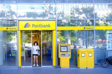 parlak sarı cephe Avrupa Bankası Postası şubesi müşterileri içeri davet ediyor, müşteri Almanya, Frankfurt 'taki ATM modern banka şubesiyle etkileşime geçiyor - 28 Mayıs 2024