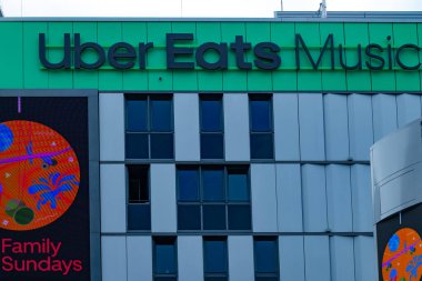 Uber Eats Music Hall Advertising logo on modern building facade, fusion of food tech and music in bustling urban setting, Berlin, Germany - August 6, 2024 clipart