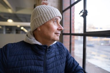 Düşünceli yaşlı adam, yalnız yakışıklı, ceketli yaşlı adam pencereden dışarı bakar, derin düşüncelere dalıp yıllar boyunca bilgelik ve tecrübeyi, altın yılları yansıtır.