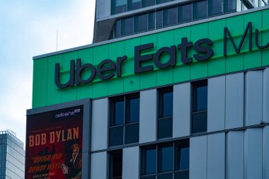 Uber Eats Music Hall Advertising logo on modern building facade, fusion of food tech and music in bustling urban setting, Berlin, Germany - August 6, 2024 clipart