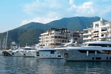 Karadağ limanı, çağdaş binalar, zarif konutlar, Tivat tatil beldesi ve yüksek yeşil dağlar tarafından desteklenen kıyı Modern Upscale marinasında sıra sıra dizilmiş lüks yatlar.