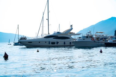 Karadağ limanı, Tivat tatil beldesi ve yüksek yeşil dağlar tarafından desteklenen Modern Upscale marinasında sıra sıra sıra sıra dizilmiş lüks yatlar.