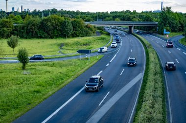 Modern çoklu şeritli otoyol, doğal manzara ufka kadar uzanıyor, yeşil ağaçlarla kaplı, aşağıda kuş bakışı hareketli trafik var, Frankfurt - 25 Ağustos 2024