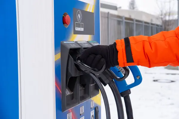 stock image man holding DC, hpc charging connector in hand, electric vehicle CCS2 lidl quick-charge station, alternative energy, technology and innovation automotive industry, Frankfurt - January 21, 2024