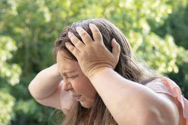 50-55 yaşlarındaki olgun bir kadın şiddetli baş ağrısı, menopoz sırasında sıcak basması, hafıza ve konsantrasyonunun azalması, gergin hissetmesi, yorgun ve bitkin hissetmesi,