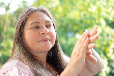 Büyüleyici olgun kadın elleri, doğal yaşlanma sürecini, kendine güvenen ifadeyi, sıcak gülümsemeyi, esansı yaşlanma ve zenginlik deneyimlerini, gençleştirme el kremini inceliyor.
