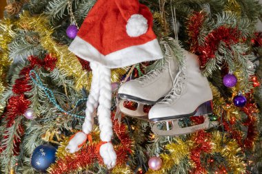 Beyaz buz patenleriyle süslenmiş Noel ağacı, kırmızı Noel Baba şapkası, kış sporları ve tatil neşesi, Noel süsleri, Noel arifesi, kış sporları, nostaljik kış harikalar diyarı