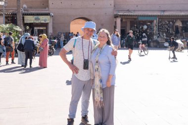 woman and man, couple tourists on ancient streets Marrakech, Jamaa el Fna Square, tradition customs Morocco, teeming with life and cultural richness, Marrakech, Morocco - January 7, 2024 clipart