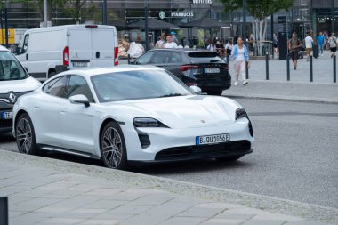 Lüks beyaz batarya elektrikli Porsche Taycan, modern kıvrımlı ve lüks performanslı şık elektrik tasarımı, kentsel çevre, Berlin, Almanya - 15 Ağustos 2024