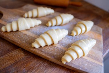 Geleneksel retro mutfak iç dekorasyonu ahşap tahtanın üzerinde pişmemiş çiğ ev yapımı yumuşak kruvasanlar fırına, ev yapımı pastaya ve pişirme hazırlıklarına hazır.