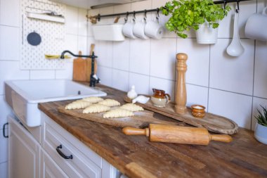 Geleneksel retro mutfak iç dekorasyonu ahşap tahtanın üzerinde pişmemiş çiğ ev yapımı yumuşak kruvasanlar fırına, ev yapımı pastaya ve pişirme hazırlıklarına hazır.