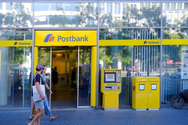 parlak sarı cephe Avrupa Bankası Postası şubesi müşterileri içeri davet ediyor, müşteri Almanya, Frankfurt 'taki ATM modern banka şubesiyle etkileşime geçiyor - 28 Mayıs 2024