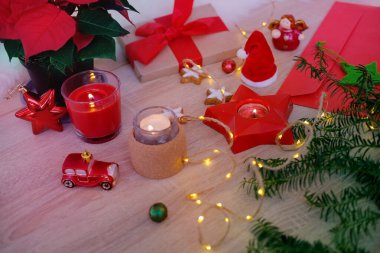 Noel öncesi dekore edilmiş masa, mumlar yakılır, çelenkler yakılır, kırmızı kurdeleli hediye, Noel 'e yakın olanlara hediye konsepti, şenlik havası, yıldızlar, şekerler, kurabiyeler dağıtıldı