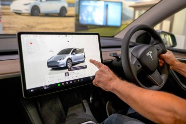 Tesla Model Y sürücüsü dikkatleri merkezi ekrana, modern sol sürücü iç dizaynına, yüksek teknoloji arayüzüne, kontrol paneline, son model otomotiv ortamına, Londra - 17 Eylül 2024