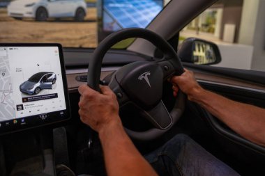 Sürücü kendinden emin bir şekilde direksiyon başında Tesla Model Y, modern sol çekişli iç mekan, sürüş deneyimi, son model otomotiv ortamı, Londra - 17 Eylül 2024