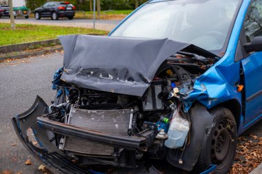 Buruşuk kaputu ve açıkta duran motoru olan ağır hasarlı bir araba, çarpışma sonrası, ön tarafında görünür hasar, kaza mahalli