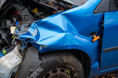 Buruşuk kaputu ve açıkta duran motoru olan ağır hasarlı bir araba, çarpışma sonrası, ön tarafında görünür hasar, kaza mahalli