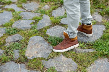 İnsan bacakları eski granit kaldırım taşı Roma yolunda duruyor Almanya 'dan geçiyor, klasik taş işçiliği ayak altında, geleneksel ortaçağ yolu, klasik antik kaldırımlı yol.