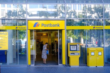 parlak sarı cephe Avrupa Bankası Postası şubesi müşterileri içeri davet ediyor, müşteri Almanya, Frankfurt 'taki ATM modern banka şubesiyle etkileşime geçiyor - 28 Mayıs 2024