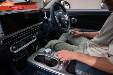 Sevimli genç erkek alıcı Genesis GV60 araç iç mekanlarını, navigasyon alanlarını, küresel merkez konsolunu, Londra 'da otomotiv endüstrisini denetliyor - 24 Ekim 2024