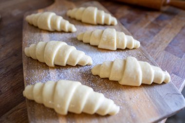 Geleneksel retro mutfak iç dekorasyonu ahşap tahtanın üzerinde pişmemiş çiğ ev yapımı yumuşak kruvasanlar fırına, ev yapımı pastaya ve pişirme hazırlıklarına hazır.