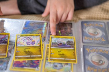 Çocuğun küçük ellerinde favori Pokmon kartı, genç hayran hevesle Pokmon kart koleksiyonu, sınırlı sayıda basım, Joy Fan Culture, Frankfurt - 18 Eylül 2024 