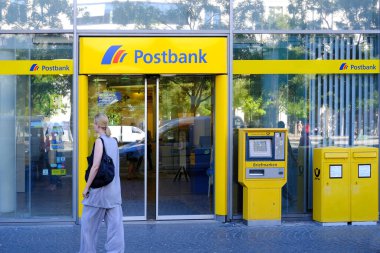 parlak sarı cephe Avrupa Bankası Postası şubesi müşterileri içeri davet ediyor, müşteri Almanya, Frankfurt 'taki ATM modern banka şubesiyle etkileşime geçiyor - 28 Mayıs 2024