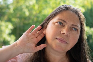 Olgun kadın kulak çınlaması, sağlık sorunları, Tinnitus semptomları, düşünceli bakışlar, psikolojik zorluklar, sağlık sorunlarını yansıtan