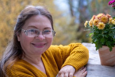 Kendine güvenen, orta yaşlı, 55 yaşında, uzun saçlı, doğal güzelliği kucaklayan, kendine güvenen, kendine güvenen, iç huzuru ve güveni olan, zamansız kadınsı bir kadın.