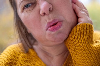 Kulaklarını acılı ifadeyle kaplayan kadın, gürültüden rahatsız olan duygusal portre, çevresel gürültü etkisi portresi, yüksek seslere kendiliğinden tepki, gerçek yüz ifadesi.