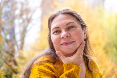 Kendine güvenen, orta yaşlı, 55 yaşında, uzun saçlı, doğal güzelliği kucaklayan, kendine güvenen, kendine güvenen, iç huzuru ve güveni olan, zamansız kadınsı bir kadın.
