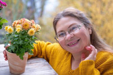 Neşeli, olgun bir kadın eğleniyor, komik bir yüz ifadesi yapıyor, neşeli hareketlerle komik bir resim yapıyor, garip bir ifade sergiliyor, açık havada kendiliğinden çekilen bir an.