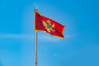 Çağdaş Karadağ bayrağı açık mavi gökyüzüne karşı dalgalanıyor, ulusal gurur, konsept turizm, göç, ekonomi ve siyaset gözler önüne seriliyor