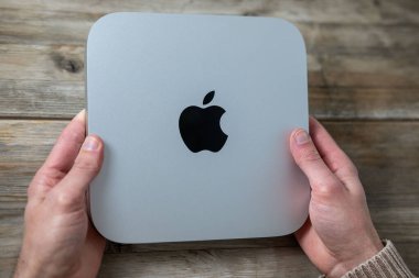 Mac Mini M1 bilgisayarı erkeklerin elinde, Apple logosu, teknolojik taşınabilirlik, uzaktan kumandalı ev ortamında çalışıyor, uzaktan kumandalı iş, vites küçülten yaşam tarzı, Frankfurt - 4 Şubat 2025