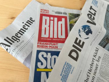 Aralarında Bild, Die Welt ve Allgemeine Zeitung 'un da bulunduğu bir yığın Alman gazetesi, tahtadan bir masanın üzerinde duruyor, basılı medya, Alman medyasını cezbediyor, Frankfurt - 15 Ocak, 2025