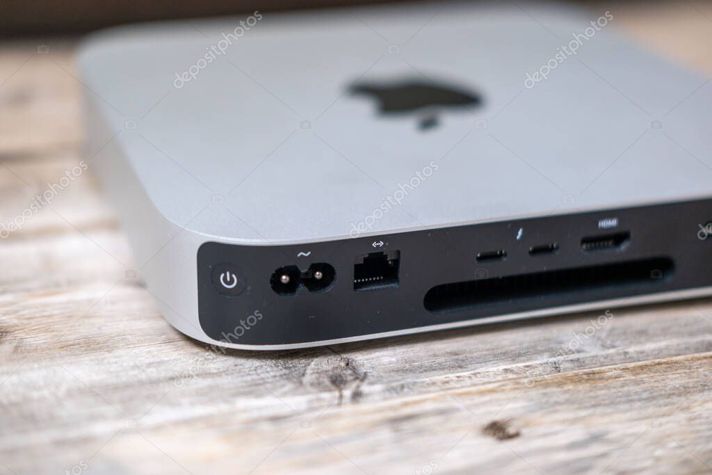 Mac Mini M1 computer and PC held, Apple logo, tech portability, working remotely in cozy home environment, home setup, remote job, downshifting lifestyle, Frankfurt - February 4, 2025