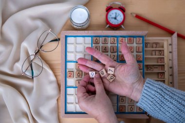 Kadınların ellerini dikkatlice Sudoku bulmacası içine yerleştirirken, meydan okuyan bulmacaları çözmeye kendini kaptırmış yaşlı insanlar, beyin sağlığı, zihinsel aktivite klasik oyunu