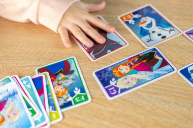 joyful child, little girl excitedly exploring Disney Frozen playing cards, connecting with magical world favorite movie, childhood hobby, Fan Culture, Frankfurt - November, 18, 2024 clipart