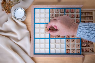 Kadınların ellerini dikkatlice Sudoku bulmacası içine yerleştirirken, meydan okuyan bulmacaları çözmeye kendini kaptırmış yaşlı insanlar, beyin sağlığı, zihinsel aktivite klasik oyunu