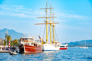 Kotor Körfezi marinasındaki lüks yatlar, Porto Karadağ 'daki son model marinaya yanaşmış, arkasında Montenegros ikonik dağları, Tivat, Karadağ - 6 Ağustos 2024 