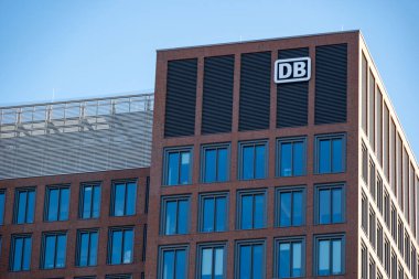 Mavi gökyüzüne karşı belirgin ikonik DB logosu olan modern bina, Deutsche Bahn şirketinin taşımacılık ve cam cephe bağlantısına karşı bağlantı, Frankfurt - 19 Ocak 2025