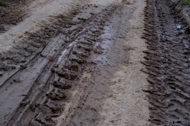 Şiddetli yağmur ve eriyen kardan sonra çamurlu yollarda lastik izleri, ıslak, çamurlu çamurlu arazide lastik izleri, off-road ortamının zorlukları.
